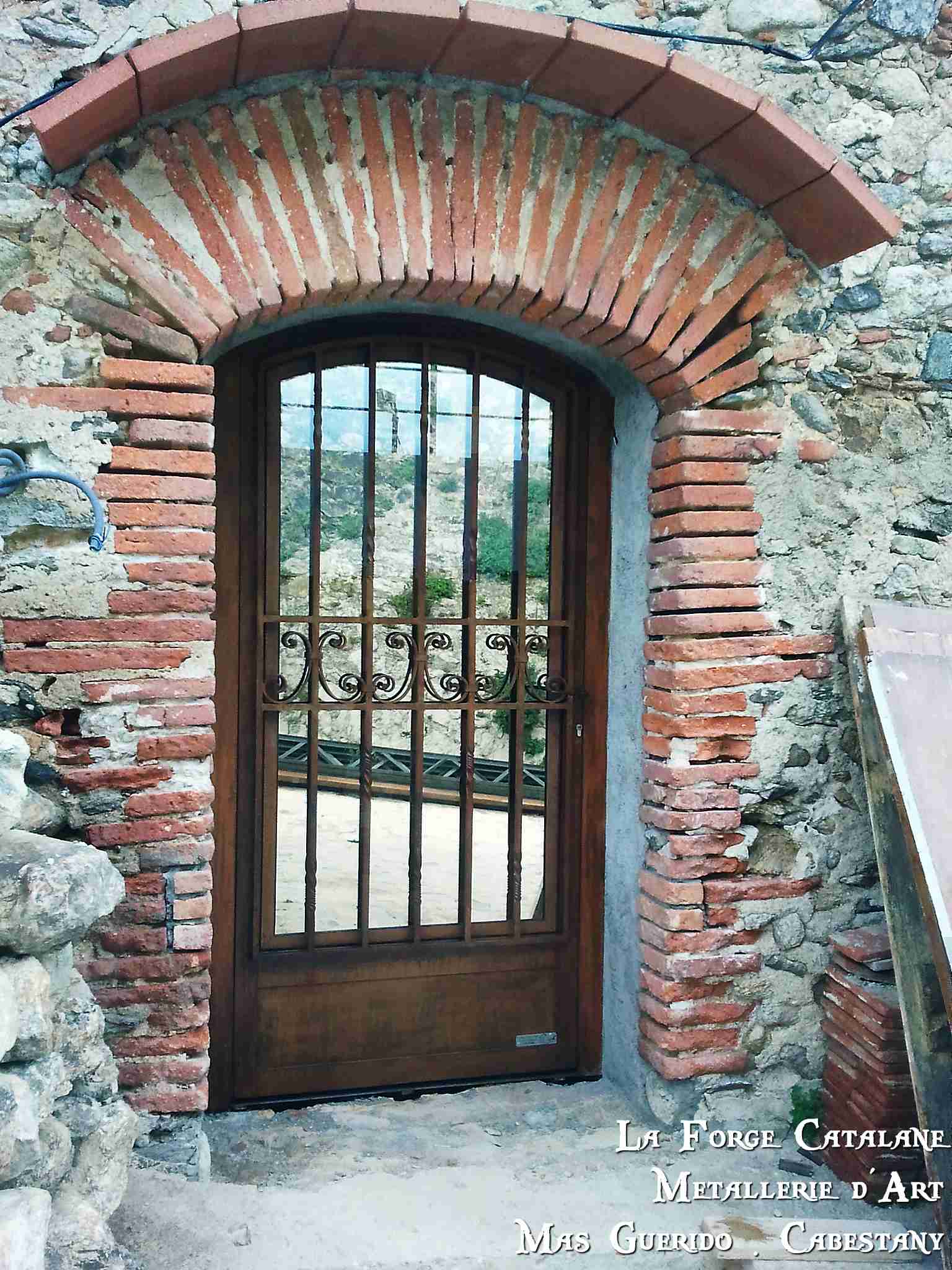 porte cintree travail a chaud volutes et vitrage espion forge catalane.jpg